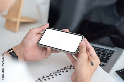 Image man holding a smartphone blank white screen at the office.