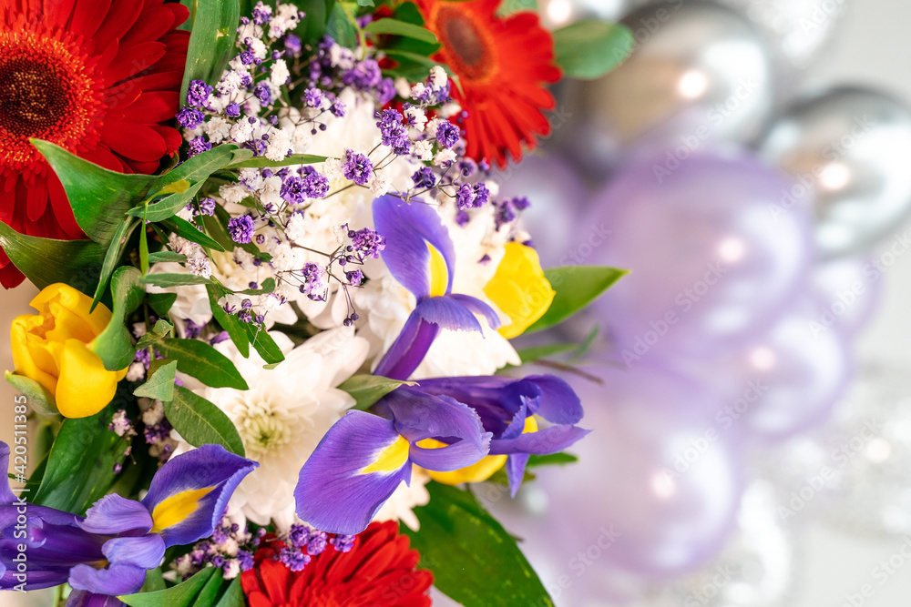 Festive purple and silver balloons fly under the ceiling and a bright bouquet of flowers, a festive concept