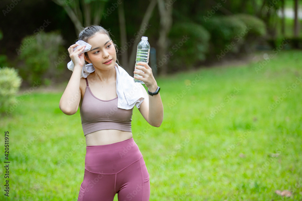 Beautiful woman doing morning exercises in exercise clothes and having clean water in bottles. On the green lawn in your front yard or park Beautiful woman doing morning exercises in exercise clothes and having clean water in bottles. On the green lawn in your front yard or park