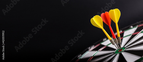 Photography Darts board with red and yellow darts arrows on center of dartboard