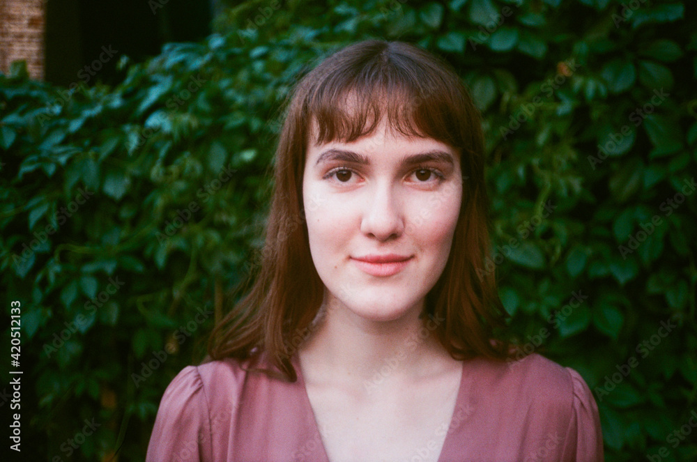 Girl's close up portrait in front of a green plant Girl's close up portrait in front of a green plant