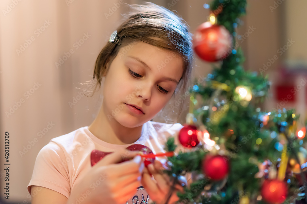 The girl decorates the Christmas tree. Children in Xmas