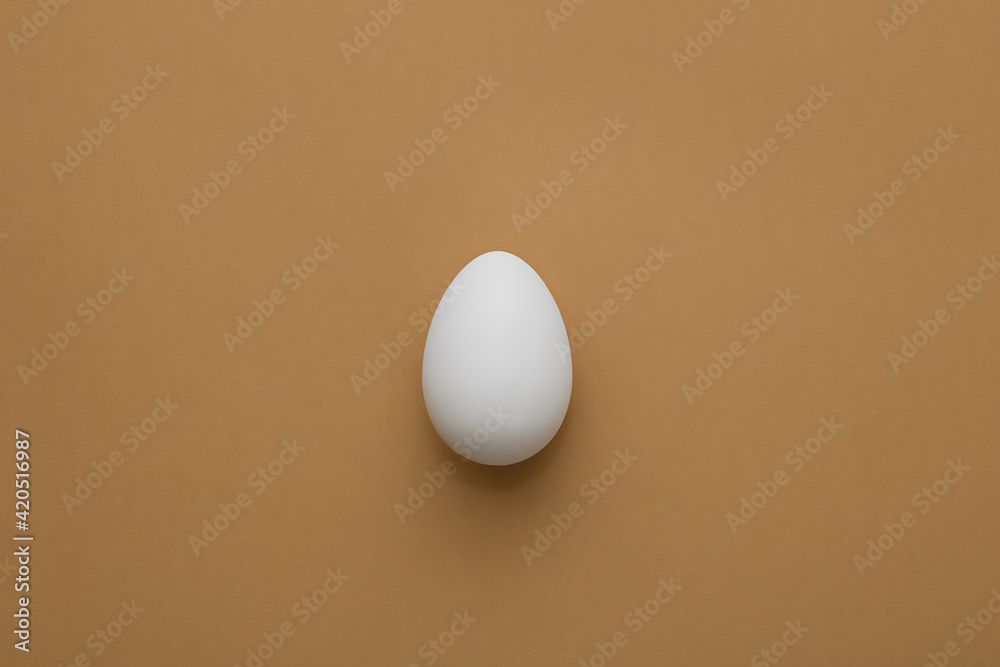 One white egg on a beige background. Minimalism. Easter eggs. One white egg on a beige background. Minimalism. Easter eggs.