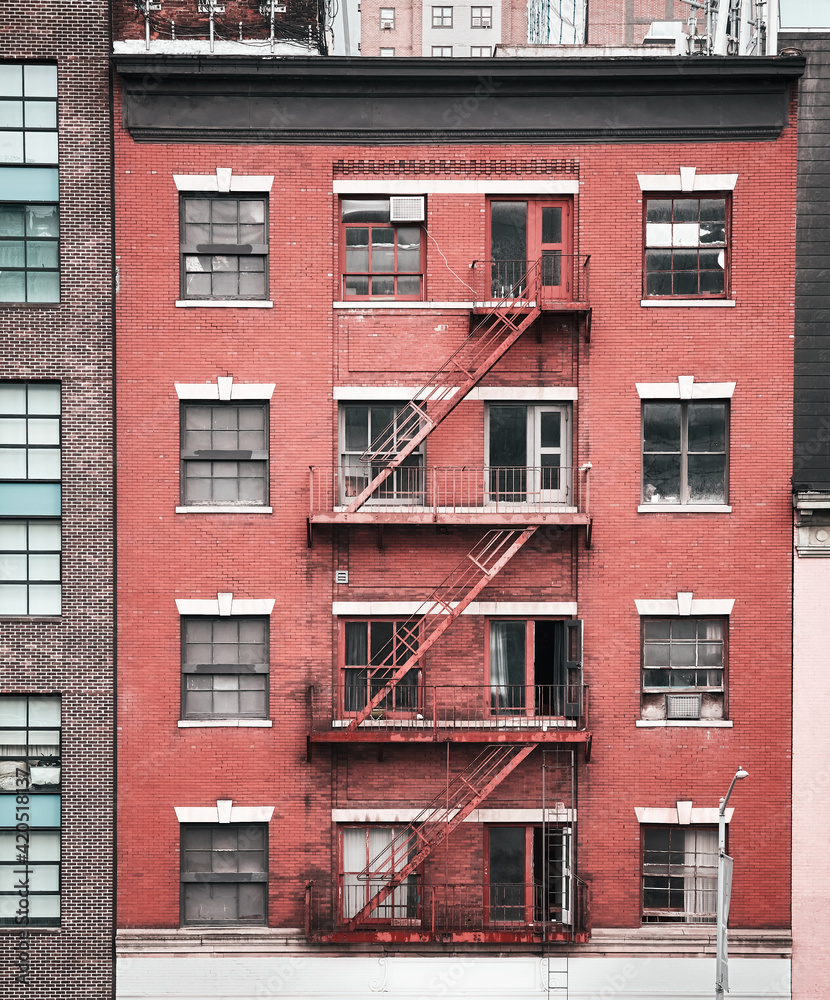 Obraz premium Old brick tenement house with fire escape, color toned picture, New York City, USA.
