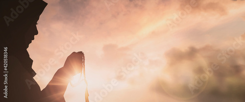 Silhouette Young muslim woman hijab honesty pray to God on sunset panoramic mosque background concept for eid mubarak, life and spiritual of islam girl fasting in ramadan, Indonesian civilian people photo