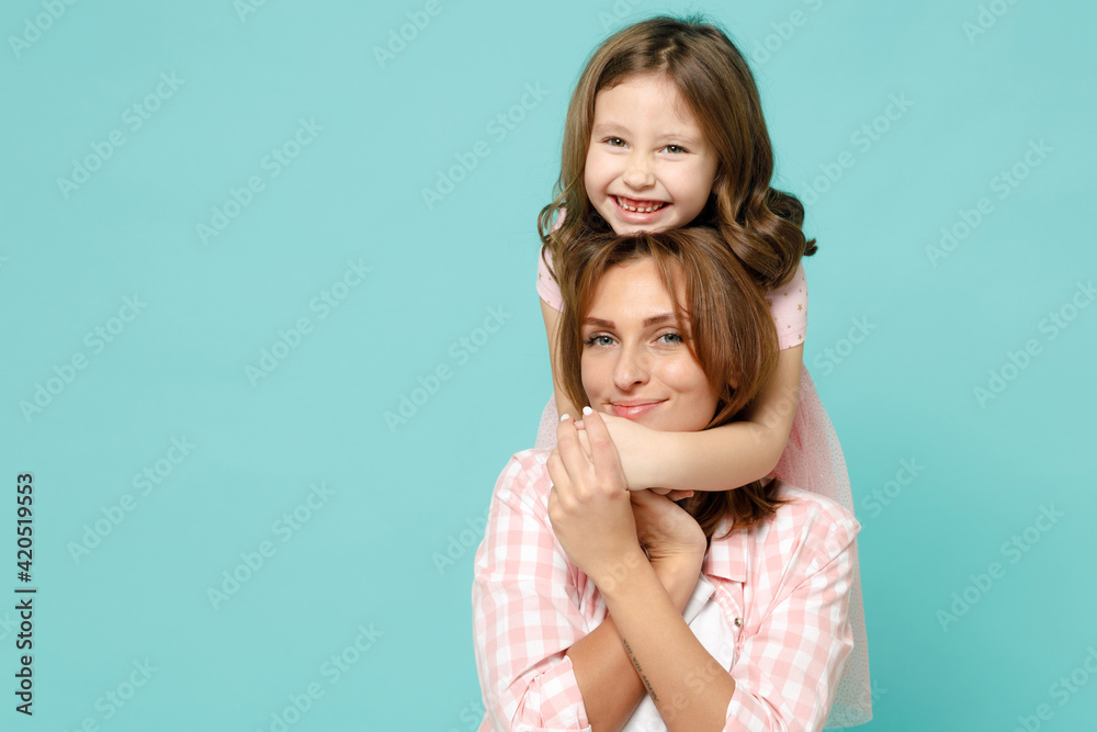 Happy woman in pink clothes have fun with child baby girl 5-6 years old Mommy little kid daughter stand behind hug kiss isolated on pastel blue azure background studio Mothers Day love family concept Happy woman in pink clothes have fun with child baby girl 5-6 years old Mommy little kid daughter stand behind hug kiss isolated on pastel blue azure background studio Mothers Day love family concept
