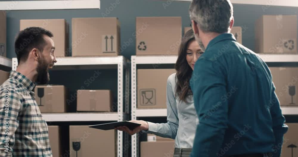 Three colleagues quarrel with each other standing in warehouse on background of cardboard boxes. Two men arrange fight out of anger. Three colleagues quarrel with each other standing in warehouse on background of cardboard boxes. Two men arrange fight out of anger.