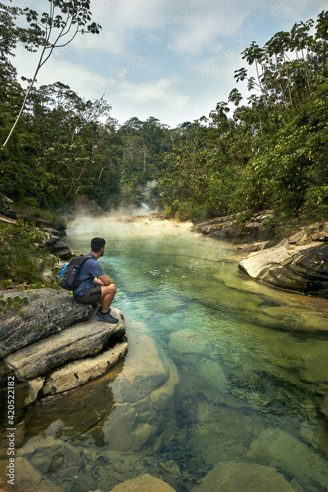 man in the rainforest watching an stunning river man in the rainforest watching an stunning river