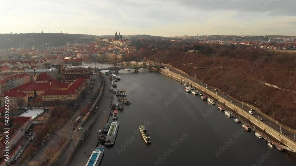 Drone shot of Prague along both banks of the Vltava River. Canal and river. Bridges over rivers. Ships and boats float on the river and stand at the pier. Cars go over the bridge over the river