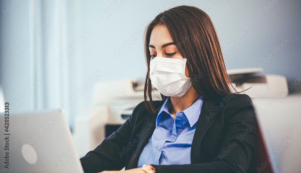 Portrait of employee woman in face mask to prevent flu virus working with computer at office desk in reopen company. new normal people lifestyle with copy space Portrait of employee woman in face mask to prevent flu virus working with computer at office desk in reopen company. new normal people lifestyle with copy space