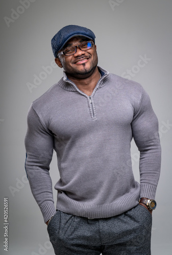 Athletic smilling fashionable model posing in studio. Muscular man in shirt smilling into camera.