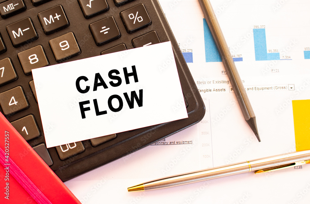 Text CASH FLOW on white card with metal pen, calculator and financial charts. Text CASH FLOW on white card with metal pen, calculator and financial charts.