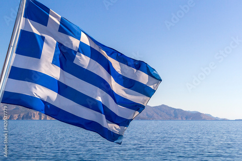 Flag of Greece on a cruise ship against greek coastline