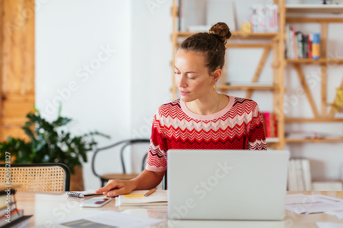 Female freelancer checking notification on smartphone