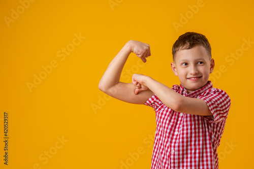 Fotografi positive, confident Caucasian 8-year-old in shirt smiles and raises his clenched