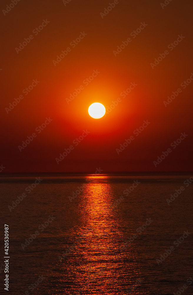 Sea sunset. Red sun on the horizon of the sea. Sunny path in the reflection of the sea.