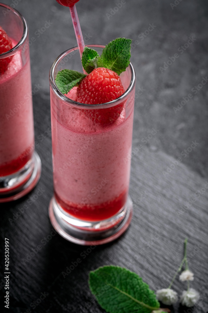 Raspberry mousse with syrup and fresh raspberries on top in glass jars on a stone background. Berry dessert with whipped cream Raspberry mousse with syrup and fresh raspberries on top in glass jars on a stone background. Berry dessert with whipped cream