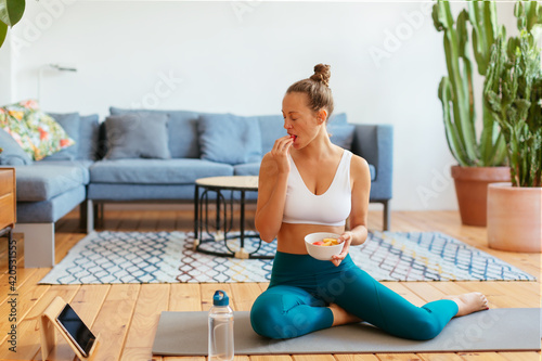 Female athlete eating healthy food and watching video