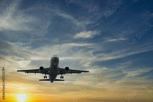The plane against the blue sunset sky. The setting sun. Sunset. Landscape with aircraft is flying in the blue sky with orange and pink clouds. The plane blue sunset sky