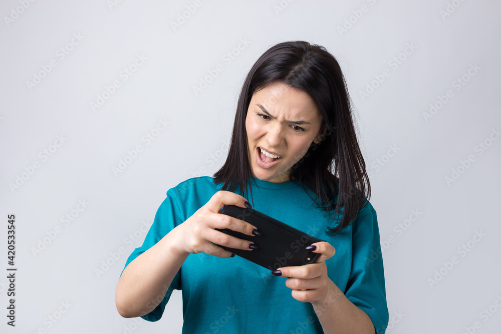 Front portrait of young smiling woman using mobile phone against grey background Front portrait of young smiling woman using mobile phone against grey background