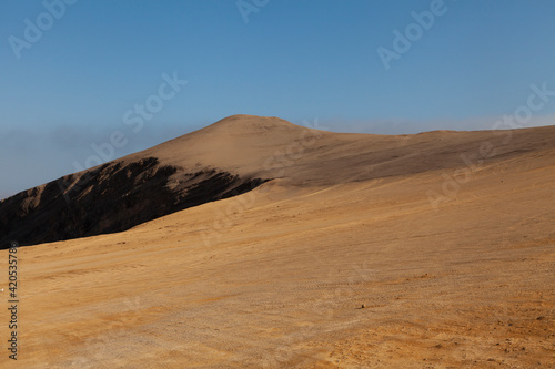 Landscape photography of red dunes and sands, near the cliffs, in the Paracas desert, on the Lagunillas Route, in the direction of Las Minas Beach in the Paracas National Reserve, Pisco, Ica, Peru.