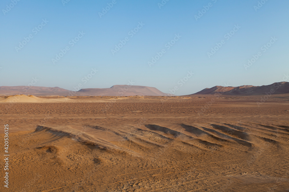 Minimalist landscape photography of red dunes and stones at sunset, in the Paracas desert, on the Lagunillas Route, in the Paracas National Reserve, Pisco, Ica, Peru.