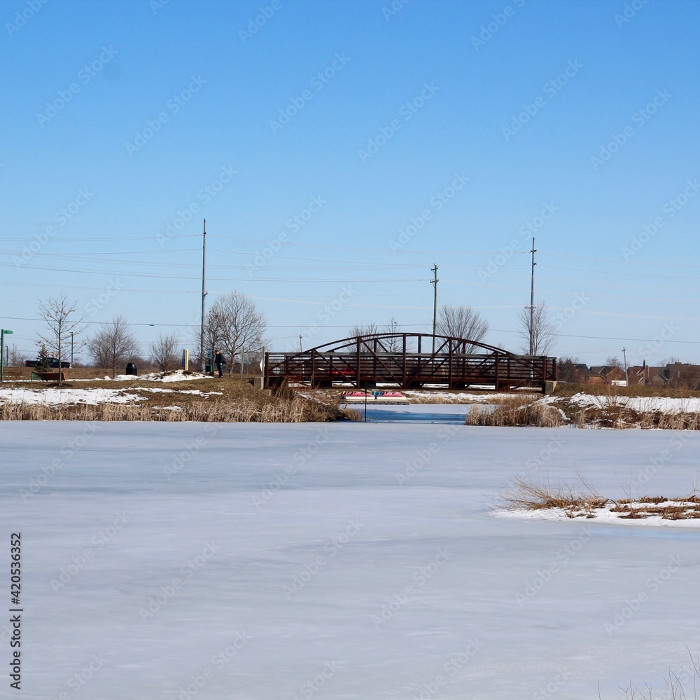 The steel footbridge over the frozen lake on a sunny day.