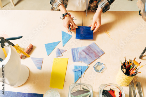 Female hands laying out a mosaic element on the table while making mosaik