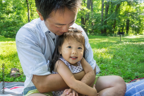 Asian father embracing todller girl outdoors photo