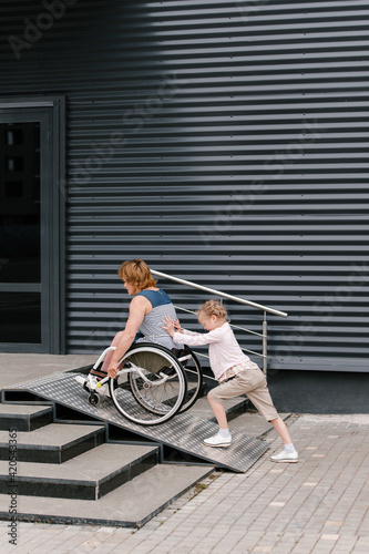 Daughter pushing mother on wheelchair on ramp photo