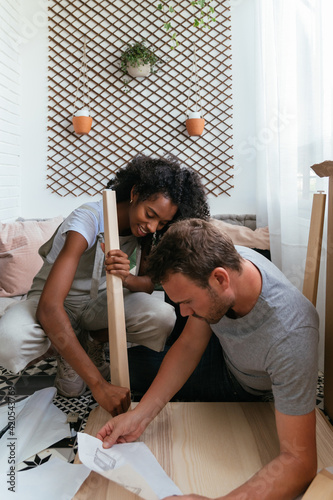 Young multiethnic couple installing furniture together
