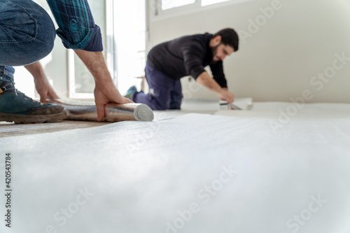 two men installing an insulating layer on the floor of the house