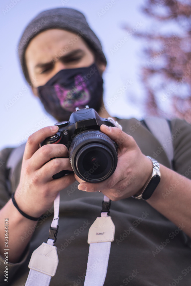 young man with mask taking photos outdoors with professional camera young man with mask taking photos outdoors with professional camera