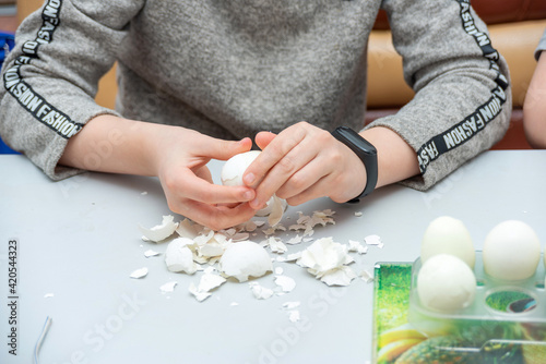 The girl peels boiled eggs from the shell for the Easter holiday