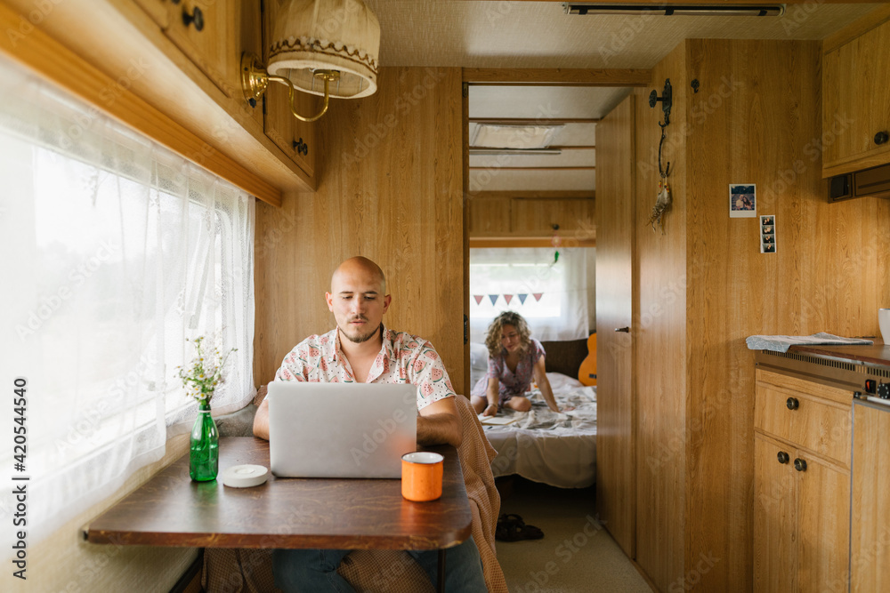Man working on his laptop in a trailer Man working on his laptop in a trailer