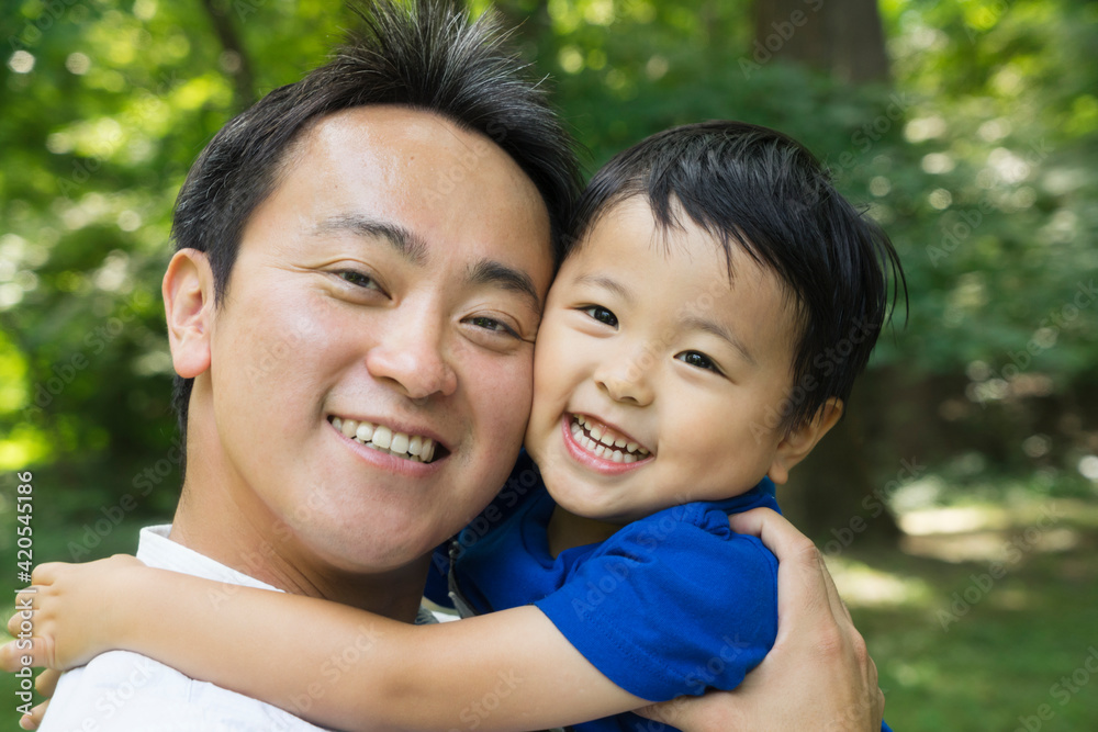 Smiling Asian father and boy portrait in green Smiling Asian father and boy portrait in green