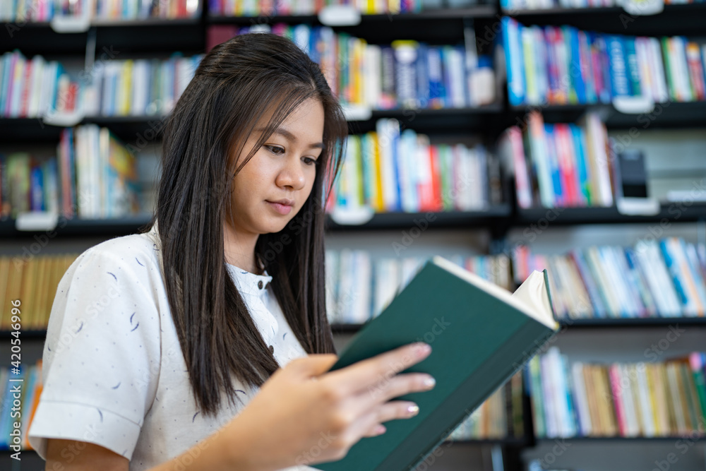 A woman is reading a book in the university library. A woman is reading a book in the university library.