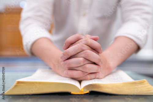 A man is reading the Holy Bible and praying in a worship room in a Christian church.