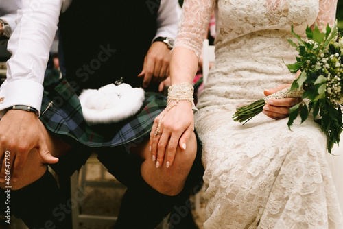 Groom wearing scottish kilt and bride wearing vintage wedding dress at ceremony