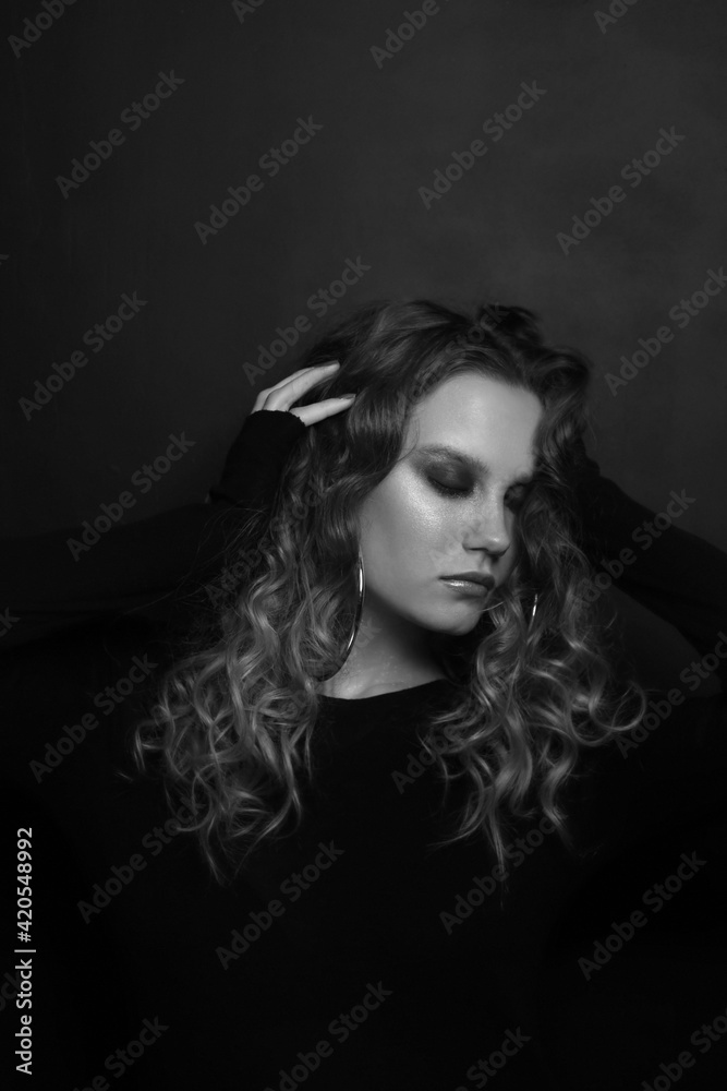 Vintage style black and white portrait of beautiful young girl with long curly hair and smoky eye makeup