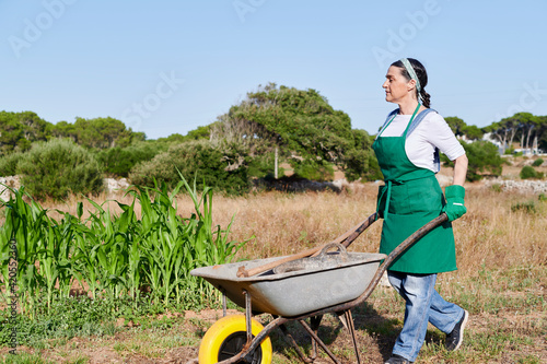 Woman pushing a wheelbarrow in her garden photo