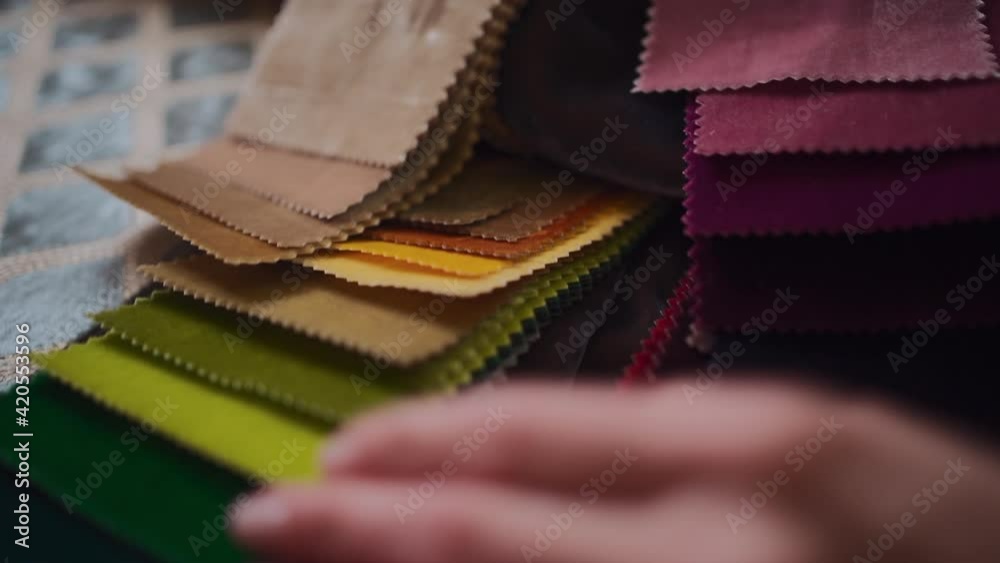 closeup of female hands choosing fabric from color palette at textile showroom