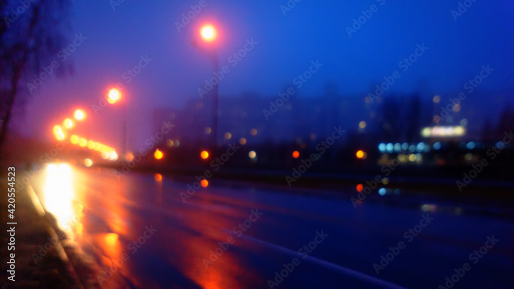 Night city and road in fog, blurred background.