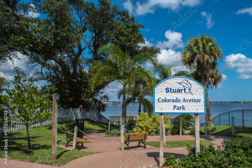 Downtown historic Stuart, Florida. Entrance to Colorado Avenue Park Healthy Trail Walk, blue sky with clouds, sunny day, lush green tropical palm trees