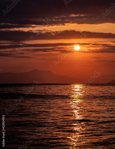 orange fiery sundwn sky with some clouds over calm sea, nature background