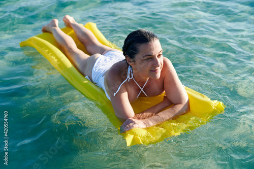 Smiling woman lying on float on the ocean photo