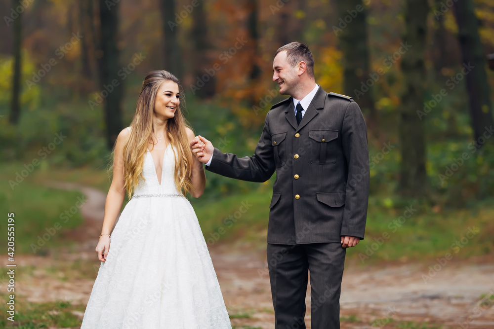 the newlyweds are holding hands and walking in the autumn park. the newlyweds are holding hands and walking in the autumn park.