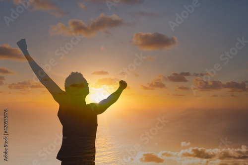 Strong young confident man with fist up to the sunset sky 