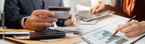 businesswoman hand using smart phone, tablet payments and holding credit card online shopping, omni channel, digital tablet docking keyboard computer at office in sun light