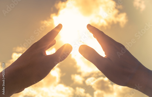 Worshiping hands touching the rays of sun light